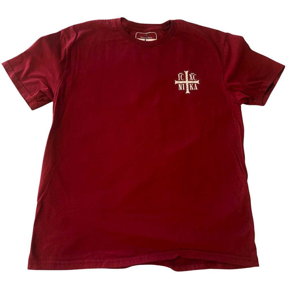 A maroon short-sleeve crewneck t-shirt with a small white cross and 'IC XC NIKA' graphic on the left chest, displayed flat against a white background.