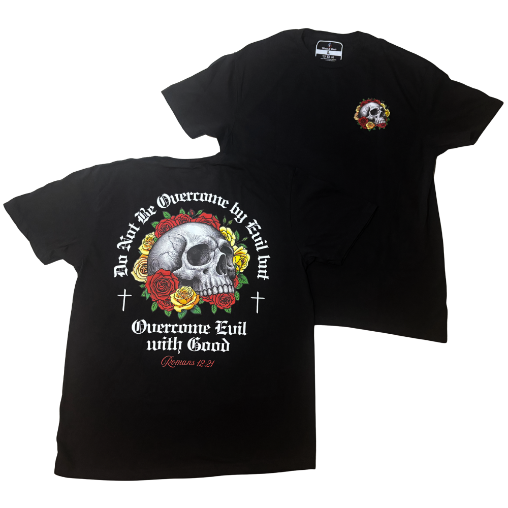 Black short-sleeve Christian graphic T-shirt shown from both front and back on a white background. The front has a small multicolor circular chest graphic, and the back features a large skull surrounded by red and yellow roses with white text reading 'Do Not Be Overcome by Evil, But Overcome Evil with Good' and 'Romans 12:21'.