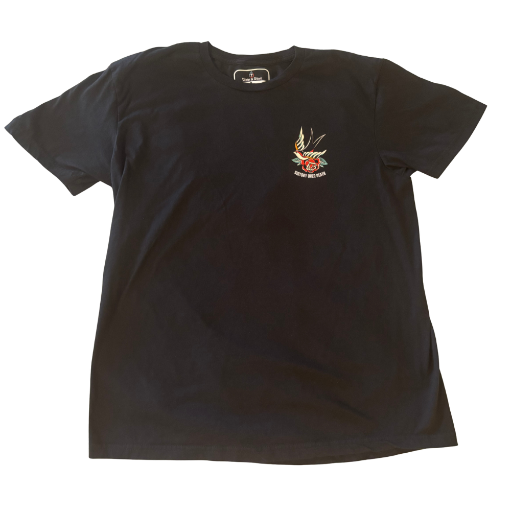 A black short-sleeve Christian t-shirt with a small left-chest graphic featuring a traditional tattoo-style bird and rose withe the text 'Victory Over Death' beneath it, displayed flat against a white background.